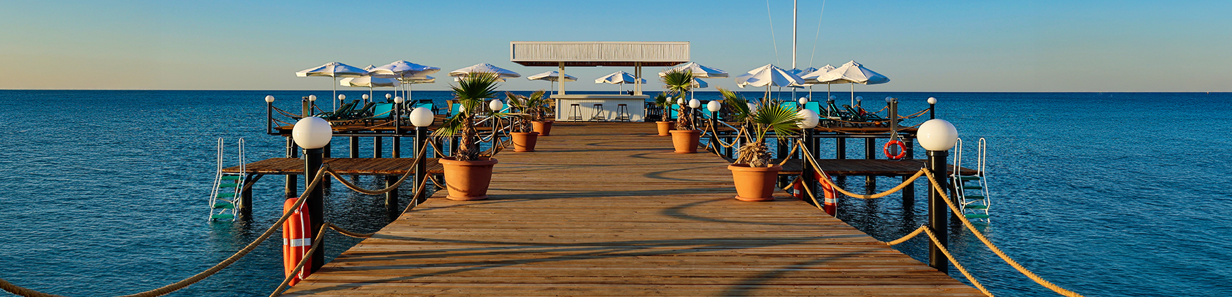 Entspannte Atmosphäre auf der Seebrücke – Sonnenliegen mit weitem Blick über das glitzernde Meer Seebrücke mit Sonnenliegen und Blick auf das ruhige Meer