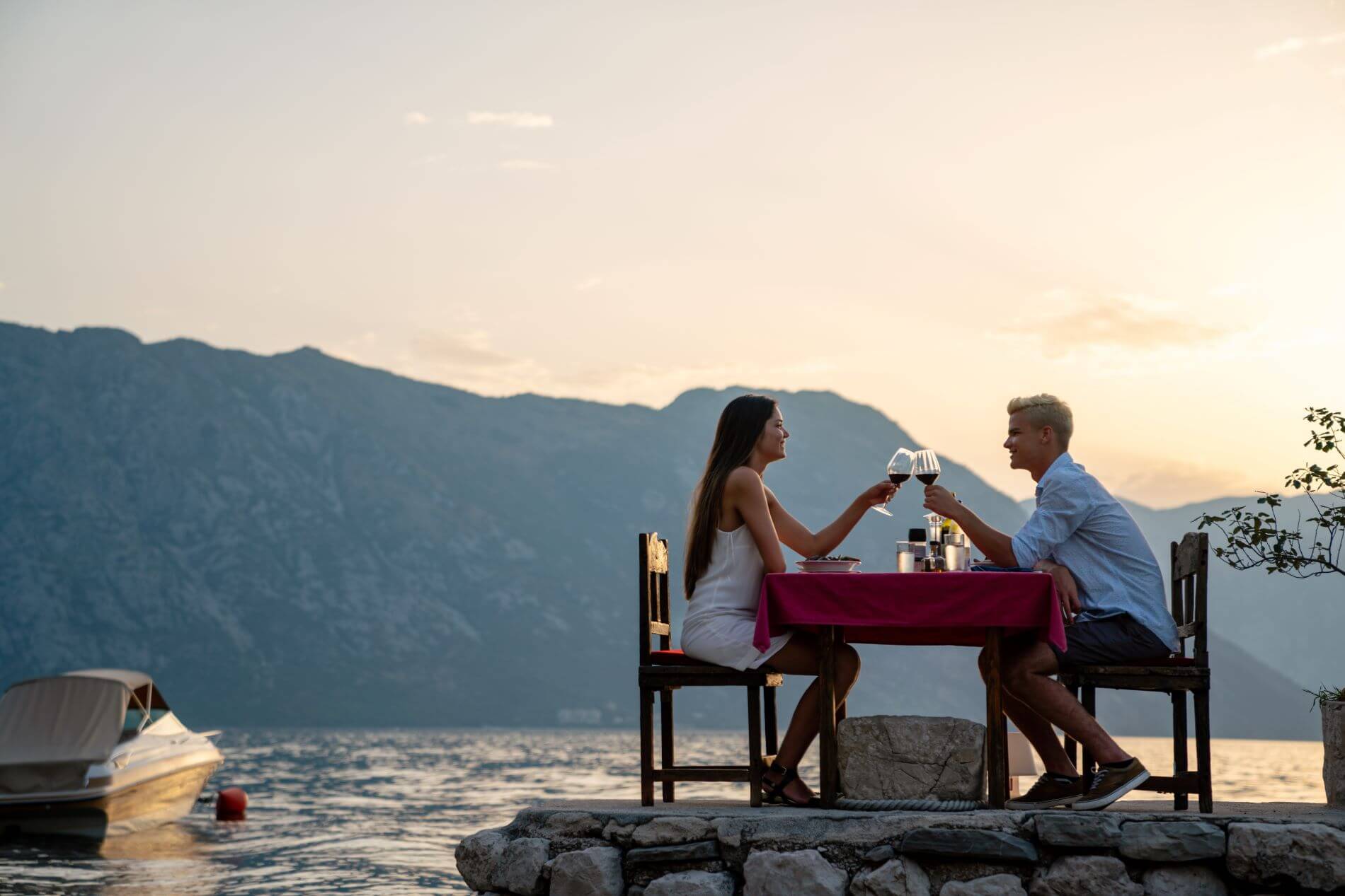 Liebespaar trinkt Wein beim romantischen Abendessen bei Sonnenuntergang am Strand.